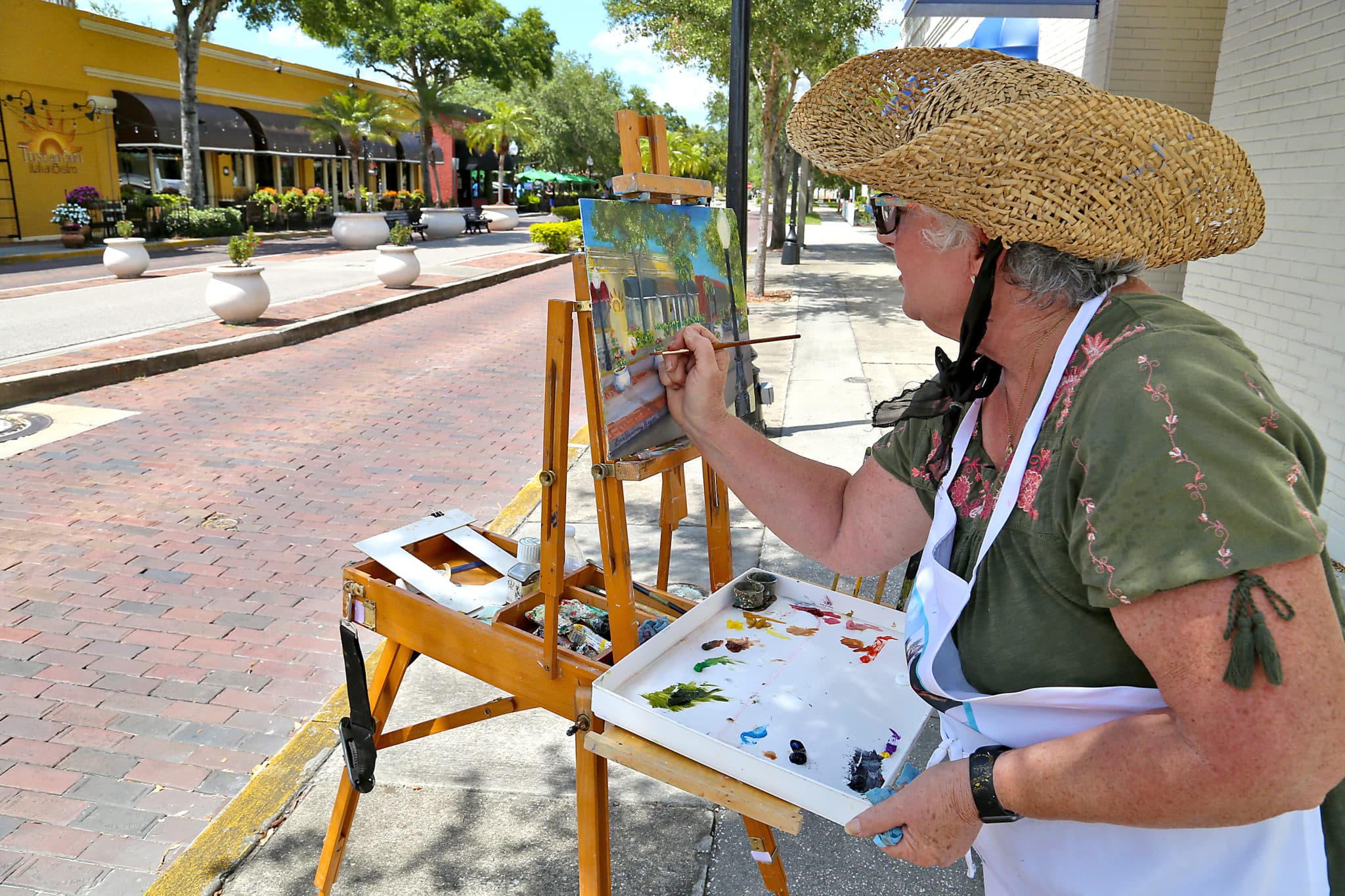 A woman on the street corner painting the row of buildings downtown